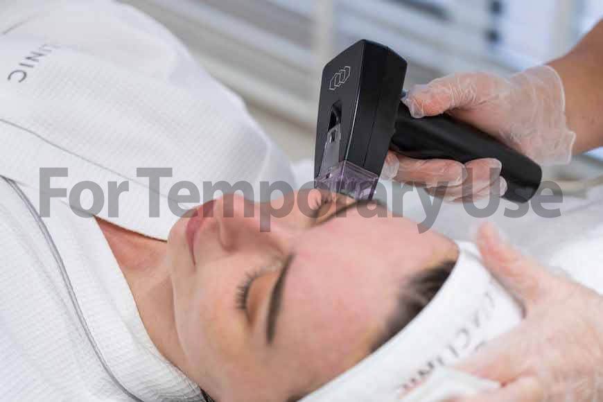 Woman receiving facial treatment; device held near face by gloved hands.