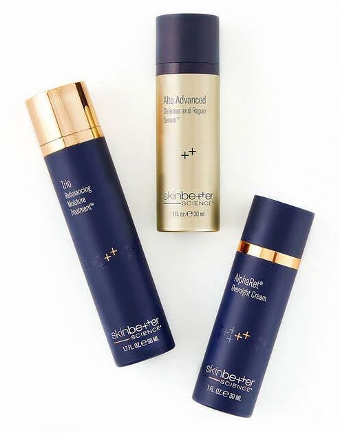 Three skincare product bottles: navy blue, gold, and white. 