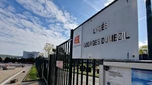 Panneau indiquant le lycée Georges Dumézil, affiché sur un portail avec un bâtiment et un ciel nuageux en arrière-plan.
