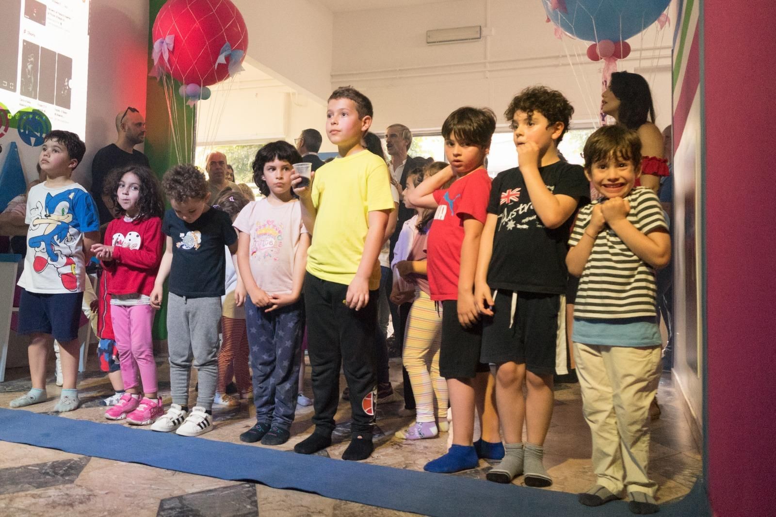 Un gruppo di bambini è in piedi uno accanto all'altro in una stanza.