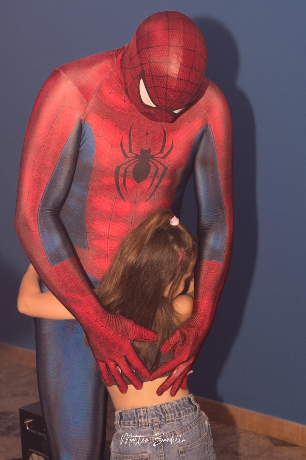 Un uomo in costume da Spiderman abbraccia una bambina