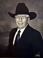A man in a suit and tie is wearing a cowboy hat and glasses.