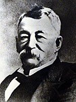 A black and white photo of a man in a tuxedo with a mustache.