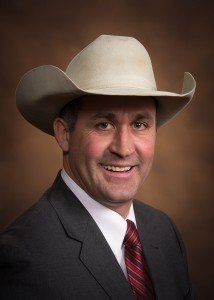 A man in a suit and tie is wearing a cowboy hat.