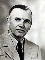 A black and white photo of a man in a suit and tie.