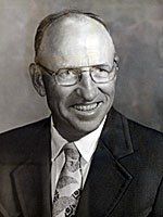 A man in a suit and tie is smiling in a black and white photo.