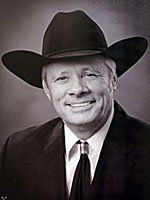 A man in a suit and tie is wearing a cowboy hat.