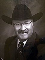 A black and white photo of a man wearing a cowboy hat and tie.