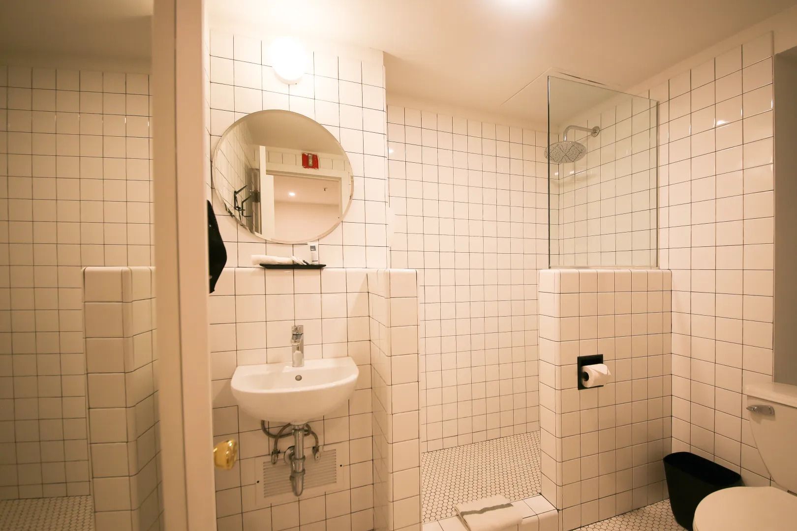 A bathroom with white tiles , a sink , toilet and shower.