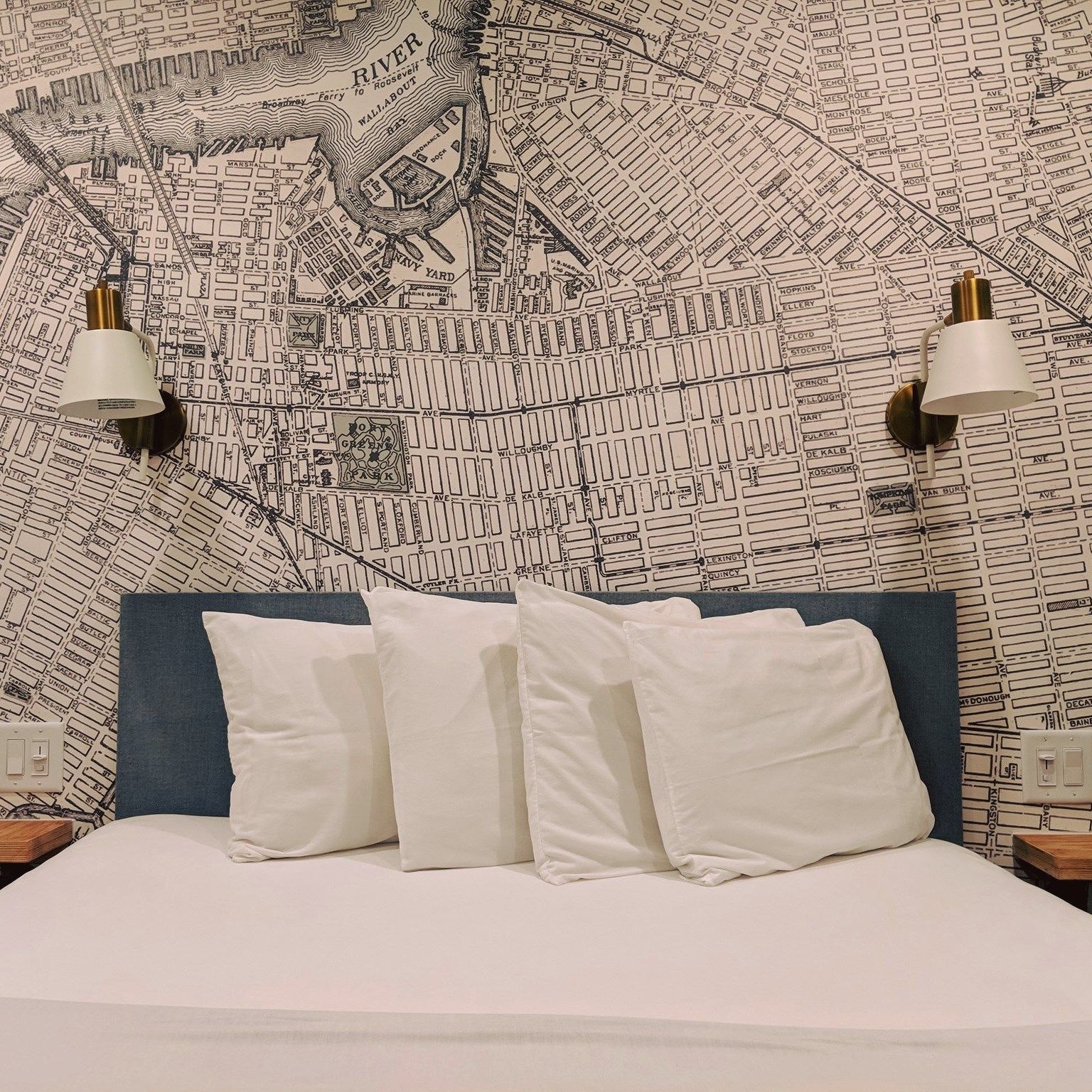 A bed with white pillows and a map on the wall behind it.