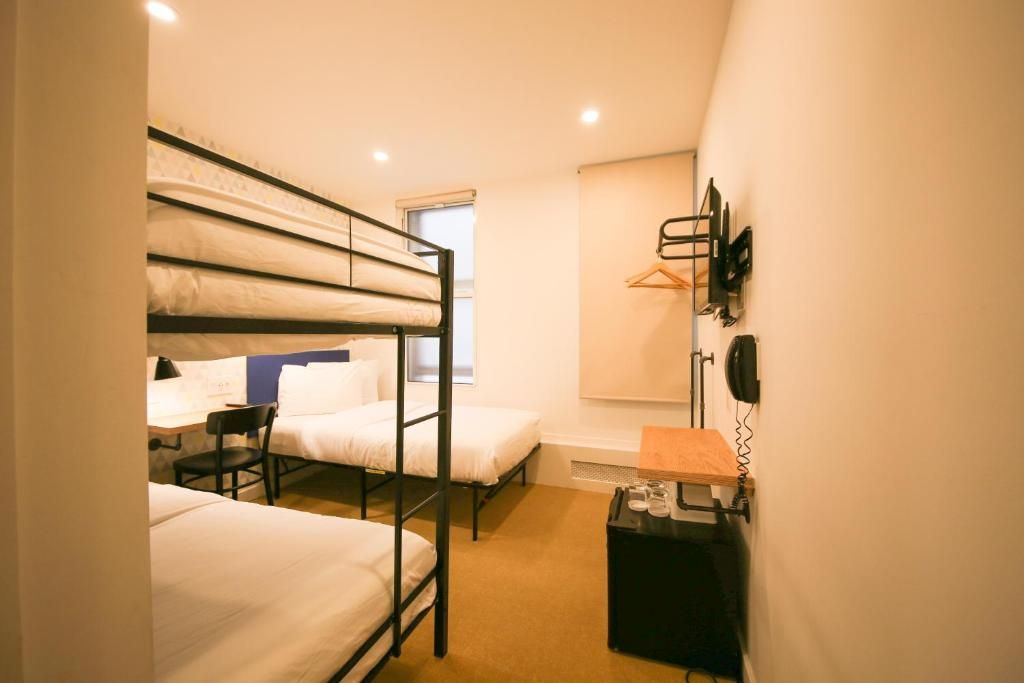 A hotel room with three bunk beds and a desk.