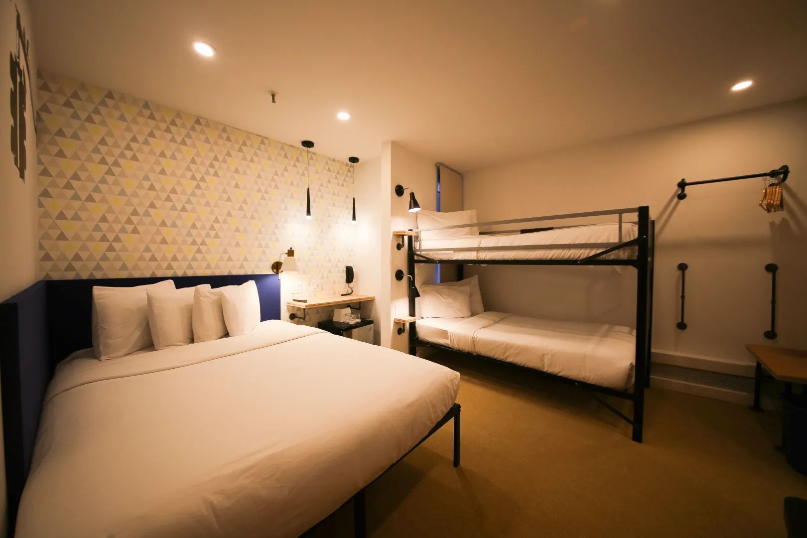 A hotel room with a bed , bunk beds and a desk.
