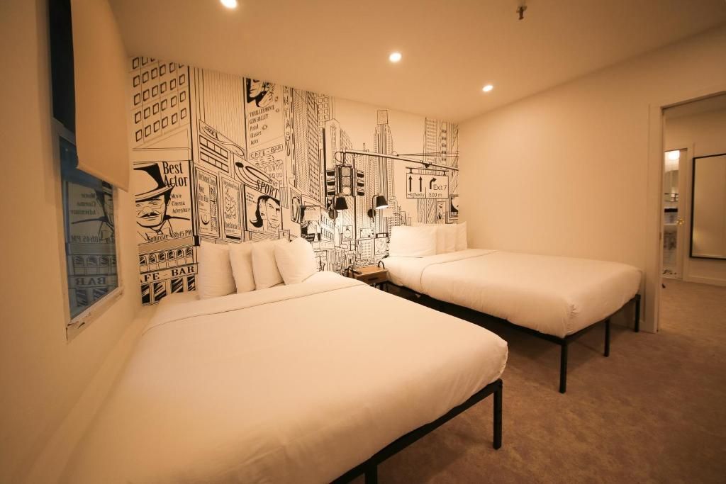 A hotel room with two beds and a mural on the wall.