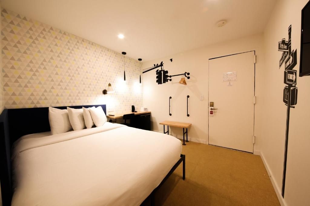 A hotel room with a king size bed and a door.