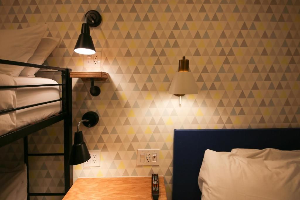 A bedroom with a bunk bed , nightstand , and lamp.