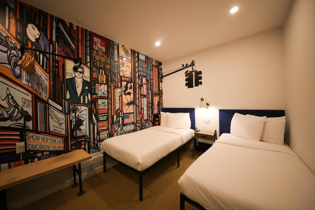 A hotel room with two beds and a mural on the wall.