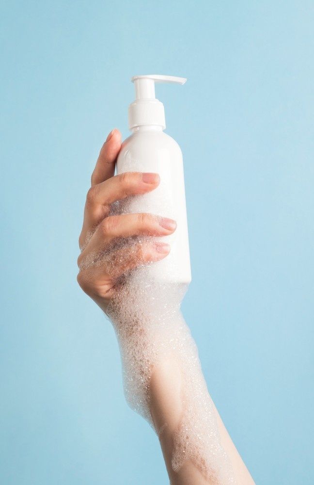 Hand Holding a White Soap Dispenser, Covered in White Foam — My Habitat Products in Mackay, QLD