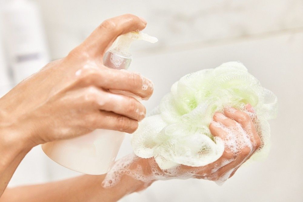 Person Squeezing Soap onto A Green Loofah in A Bathroom — My Habitat Products in Townsville, QLD
