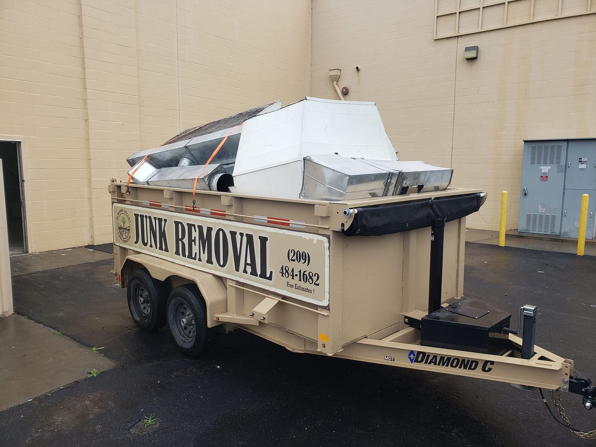 A sink removal trailer is parked in front of a building.