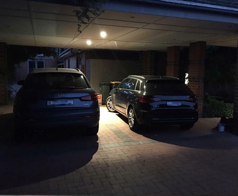 Two cars are parked in a driveway at night