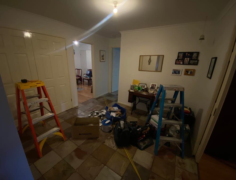 A room with a ladder and boxes on the floor.