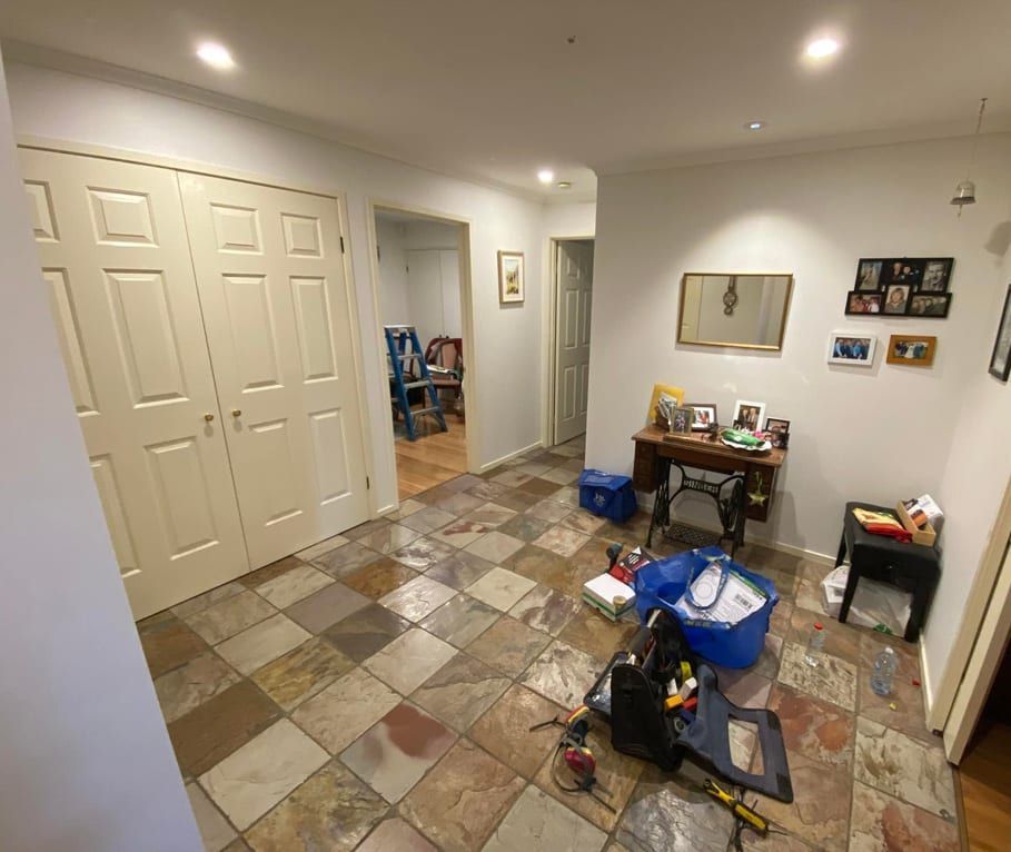 A hallway with a tiled floor , a desk and a mirror.