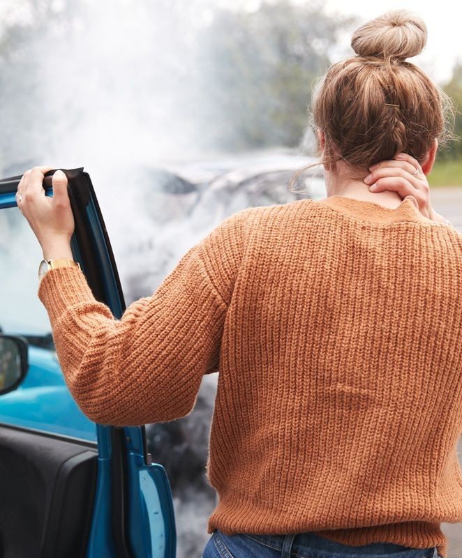 A woman surveying the damage after a bad car wreck.