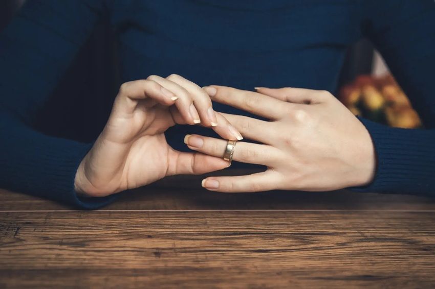 A woman is taking off her wedding ring, possibly hinting at divorce