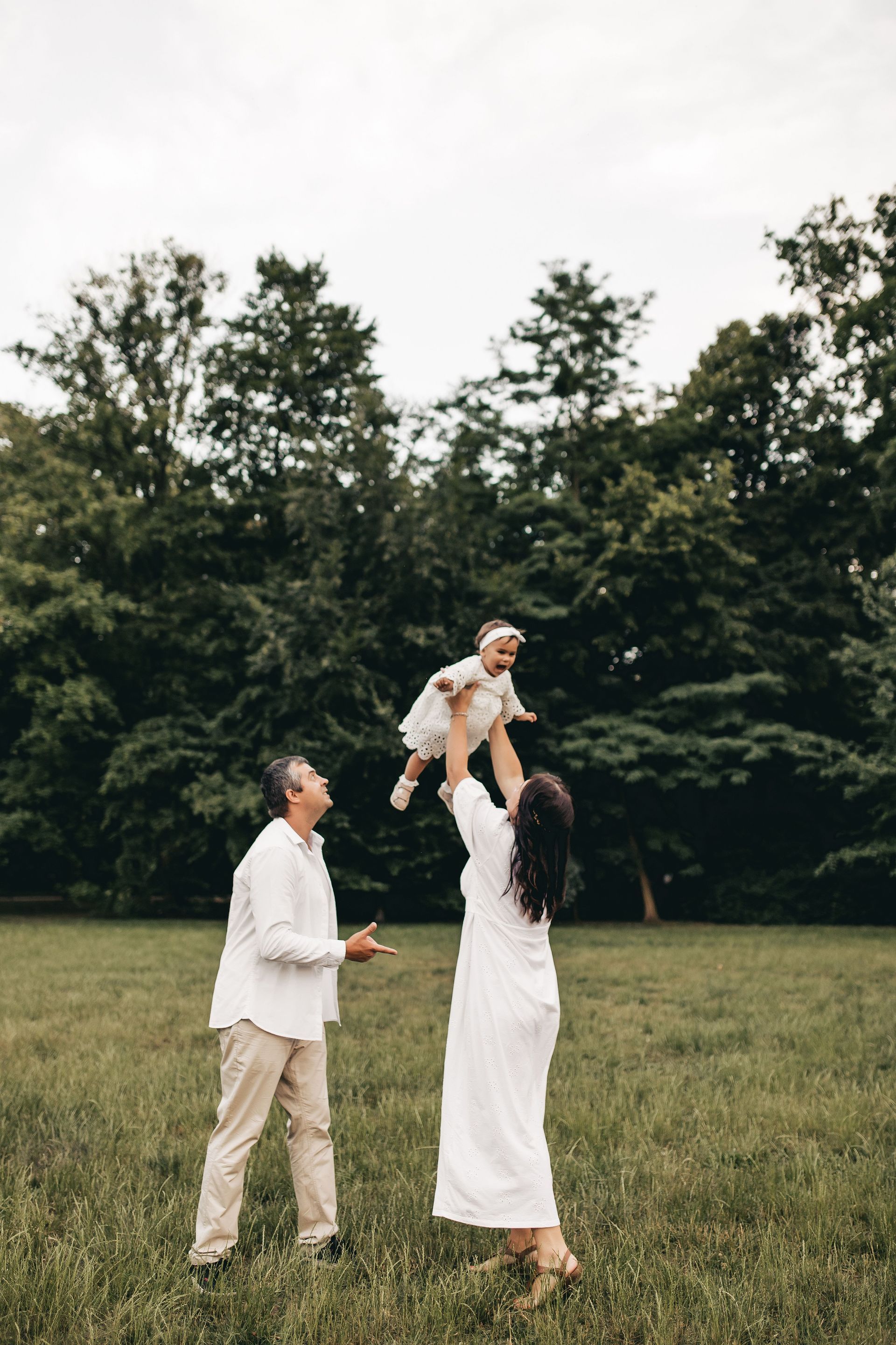 A man and woman playing with their baby outside