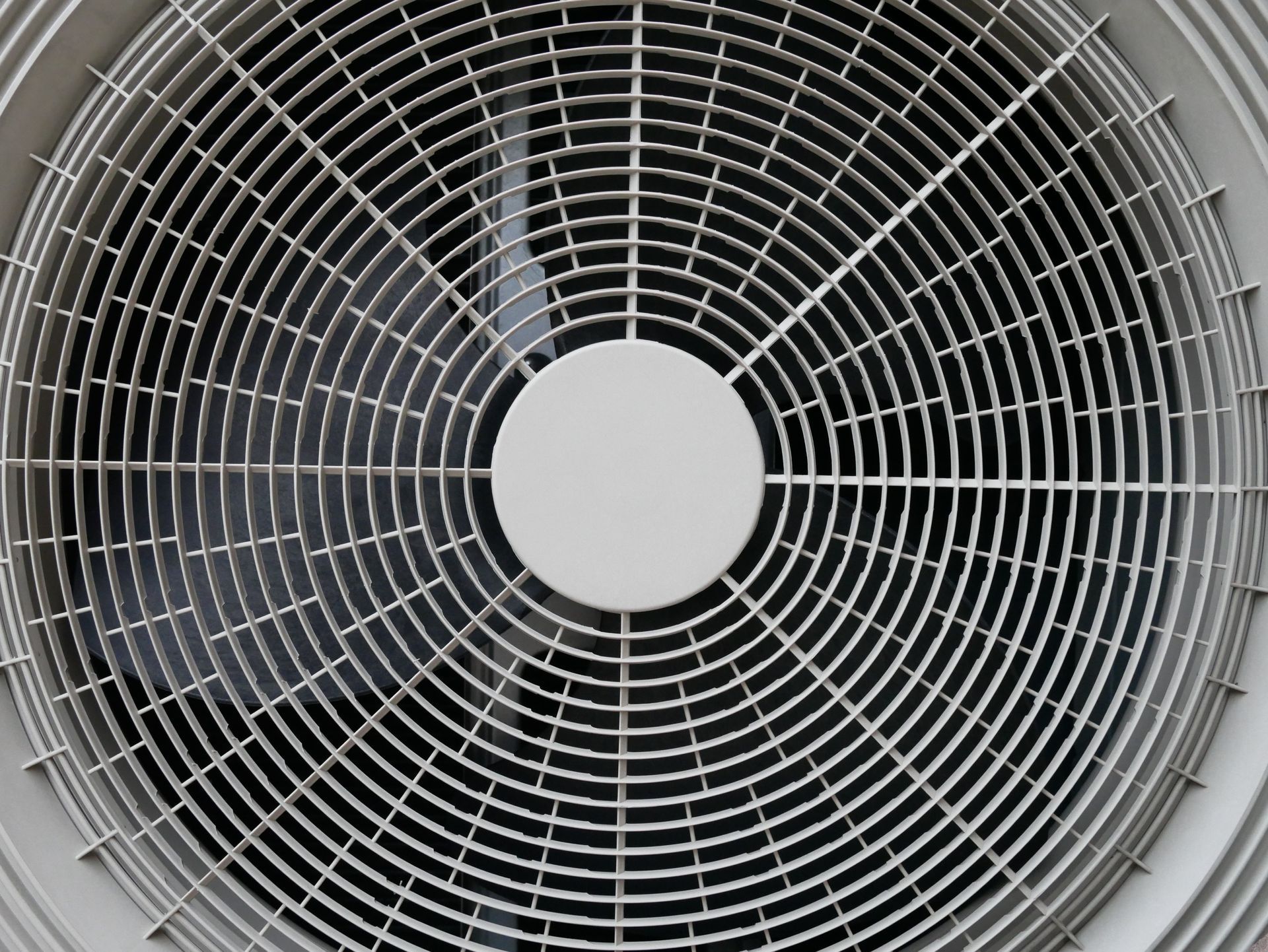 HVAC technician tools, including a manifold gauge set with red and blue dials, connected to an outdoor air conditioner.