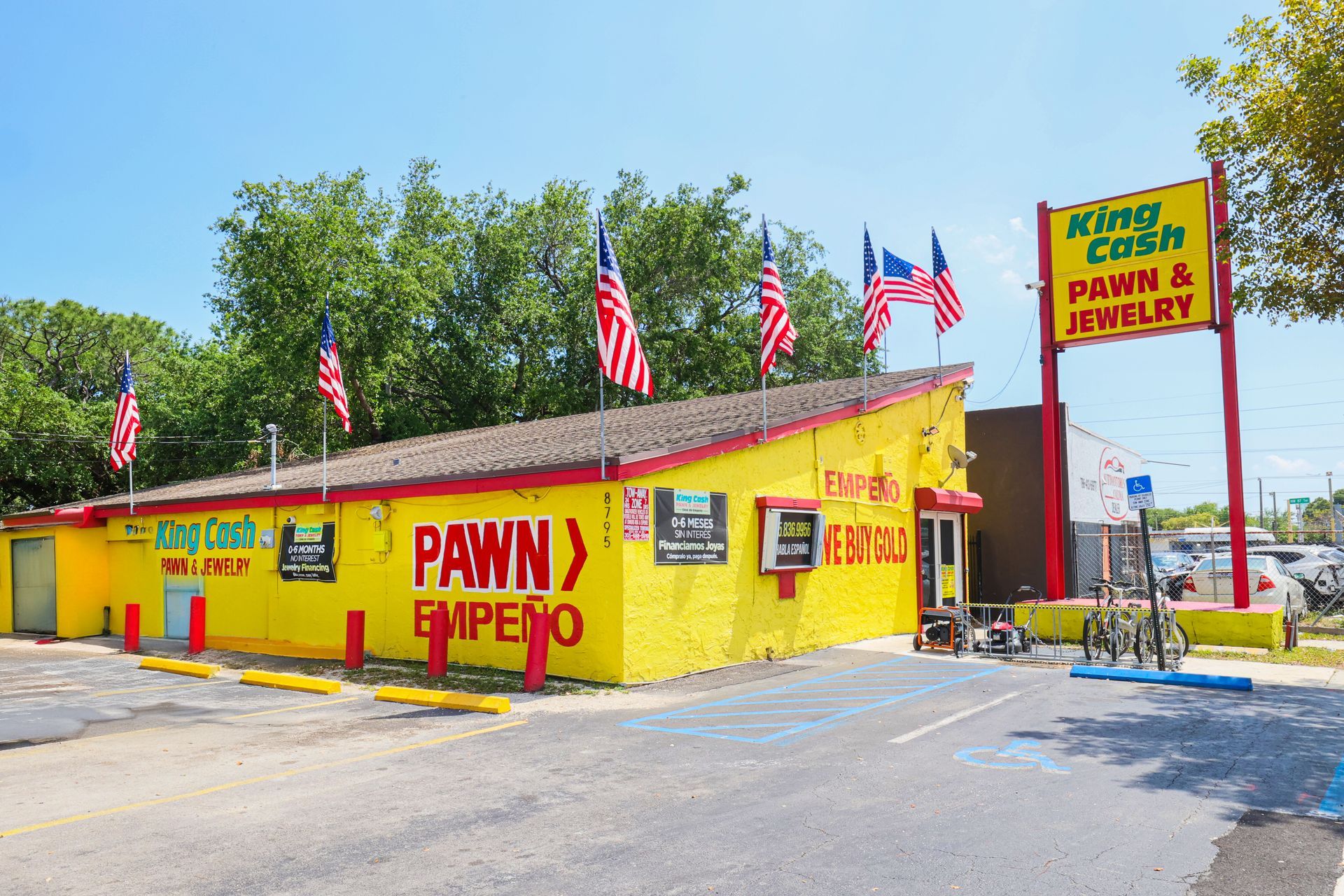 Exterior view of King Cash Pawn & Jewelry store on Miami 27th Avenue with yellow facade, and multiple American flags.