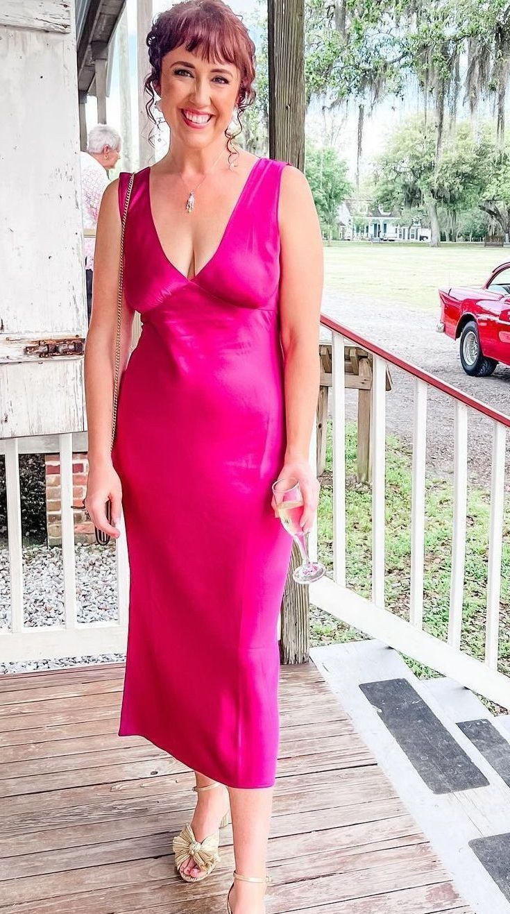 A woman in a pink dress is standing on a porch.