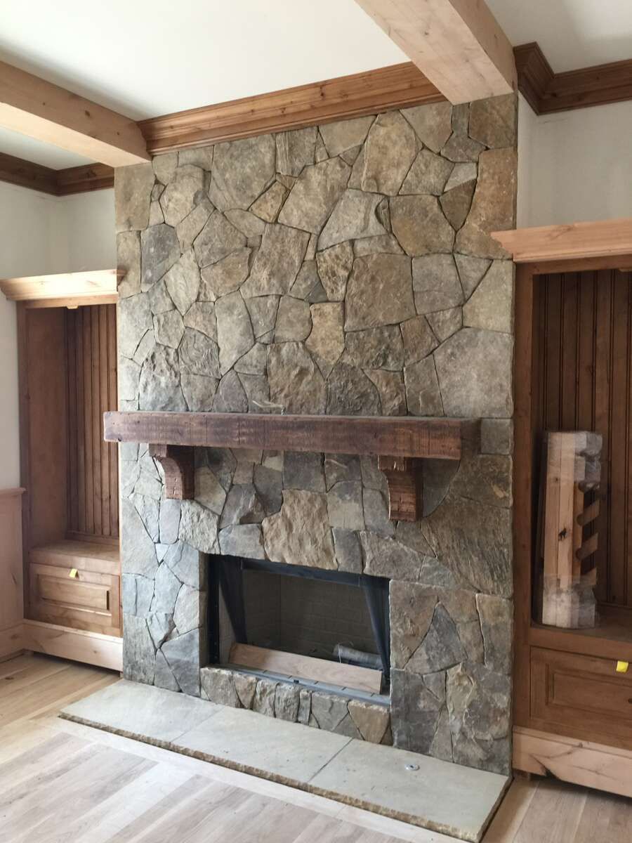 Stone fireplace with wooden mantel and built-in bookshelves. Beige, gray, and brown tones.