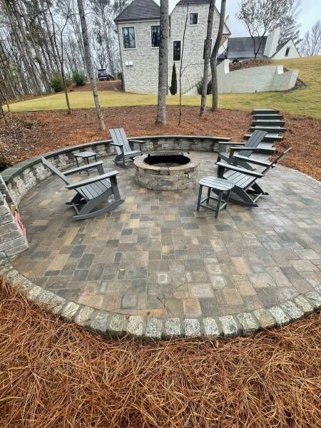 Round paver patio with fire pit and seating, steps leading up to grass.