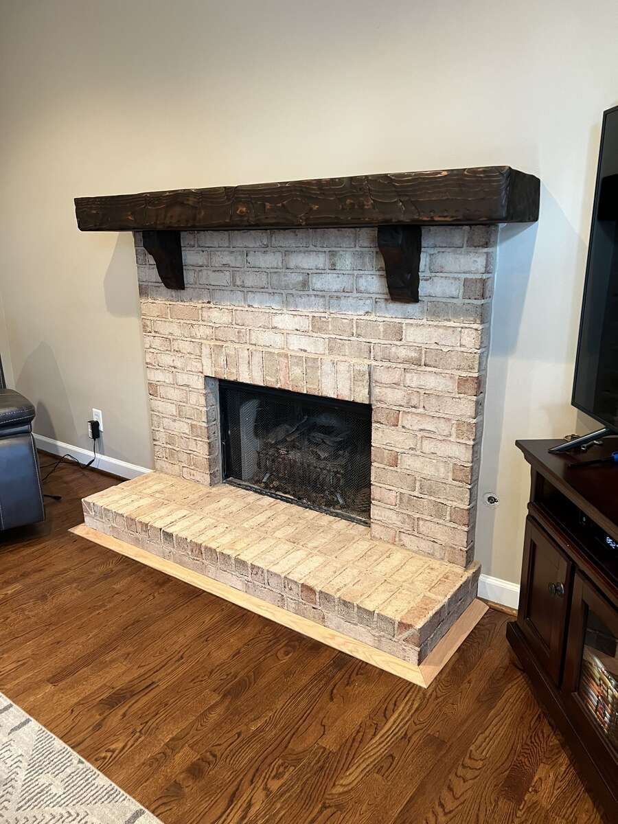 Brick fireplace with a dark wooden mantel and hearth.