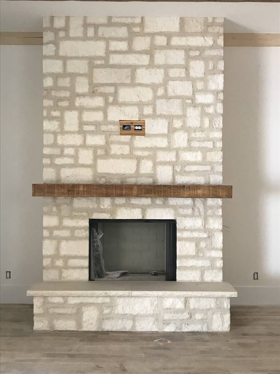 Stone fireplace with wooden mantle and light-colored stone surround and base.