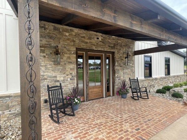 Stone and wood porch with rocking chairs and brick floor.