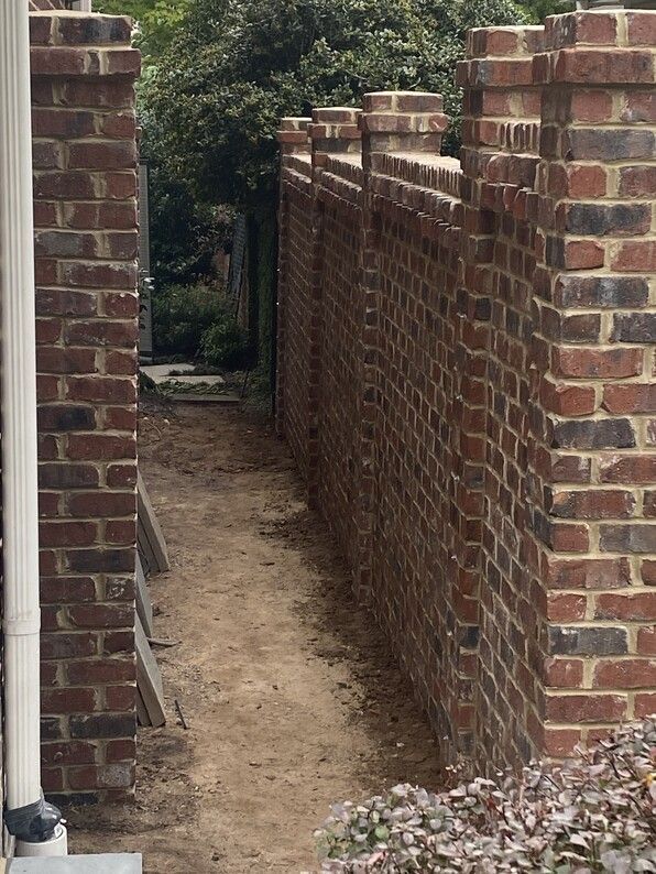 Brick walls with a narrow dirt pathway between them.