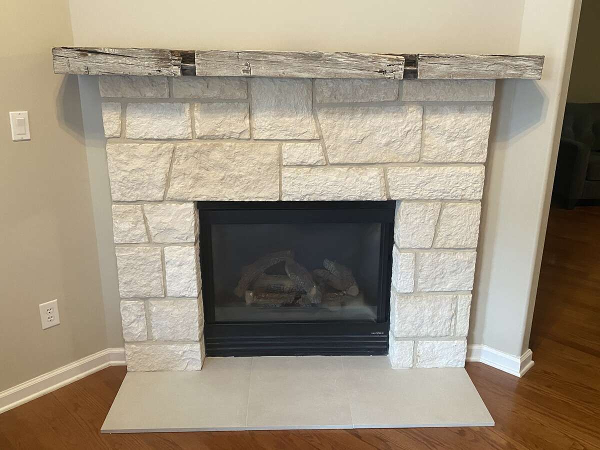 Stone fireplace with wooden mantle and black firebox.