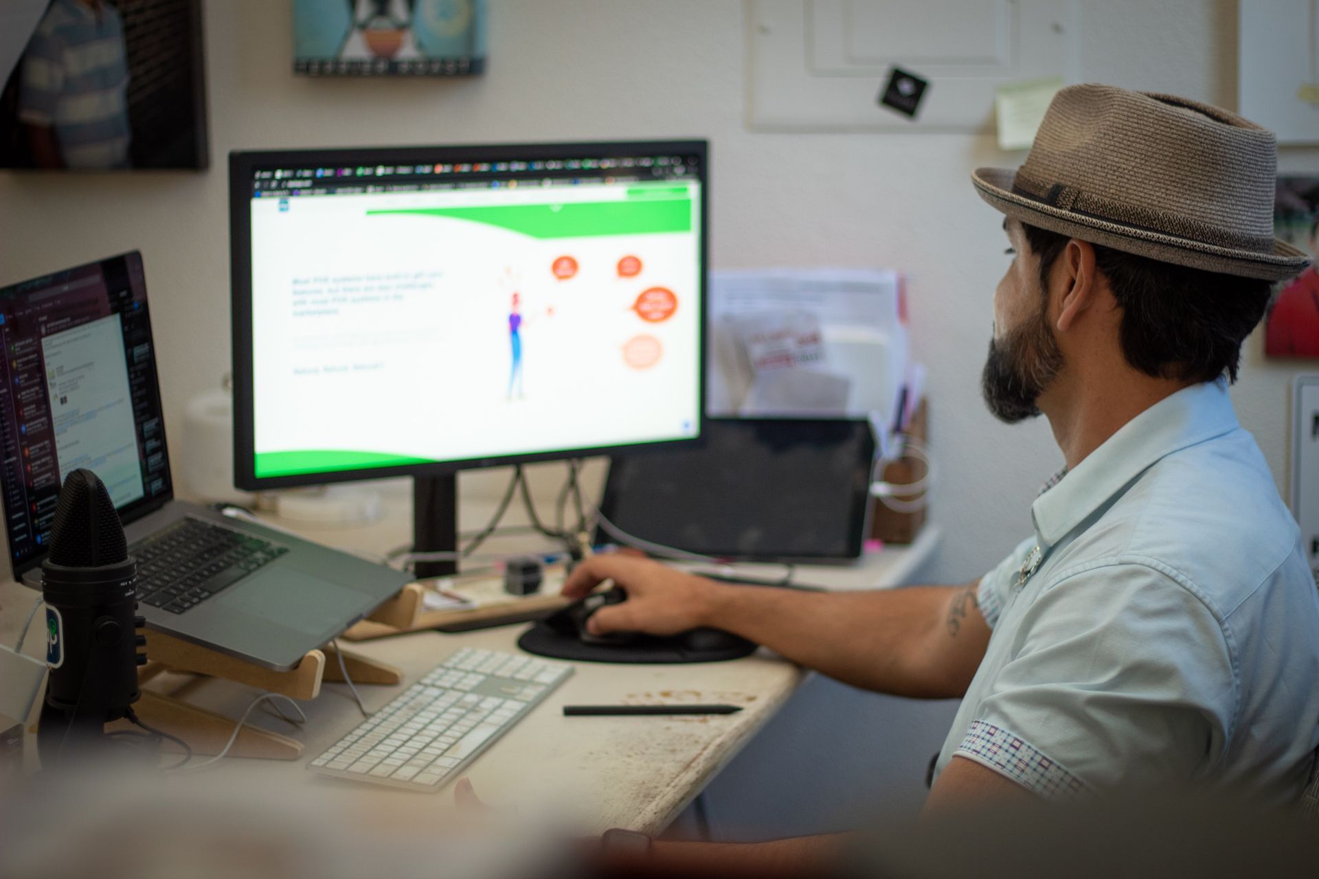 Person working at a desk with dual monitors, viewing a design interface in a home office