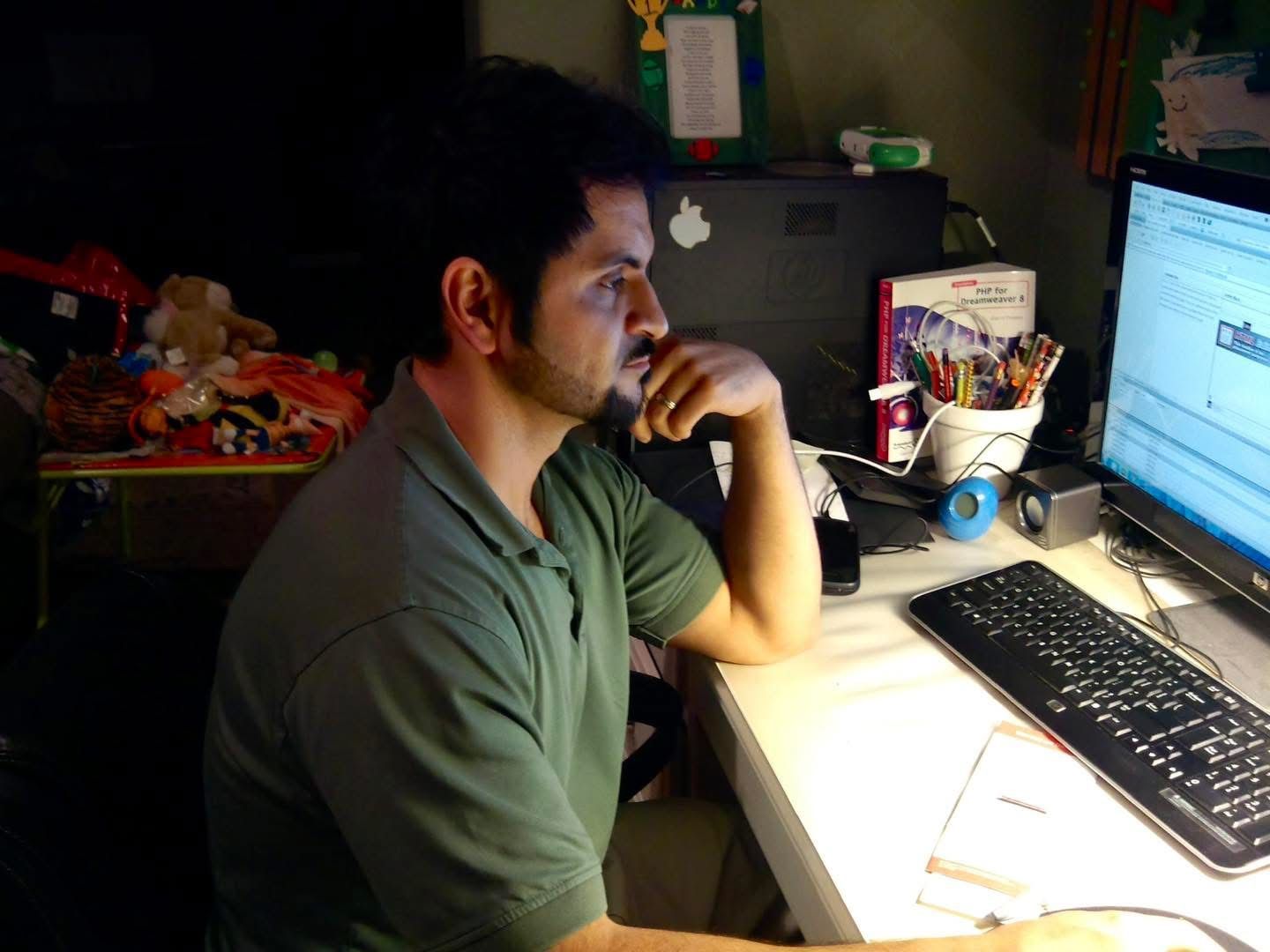 cesar torres looking at a computer working on a website through dreamweaver