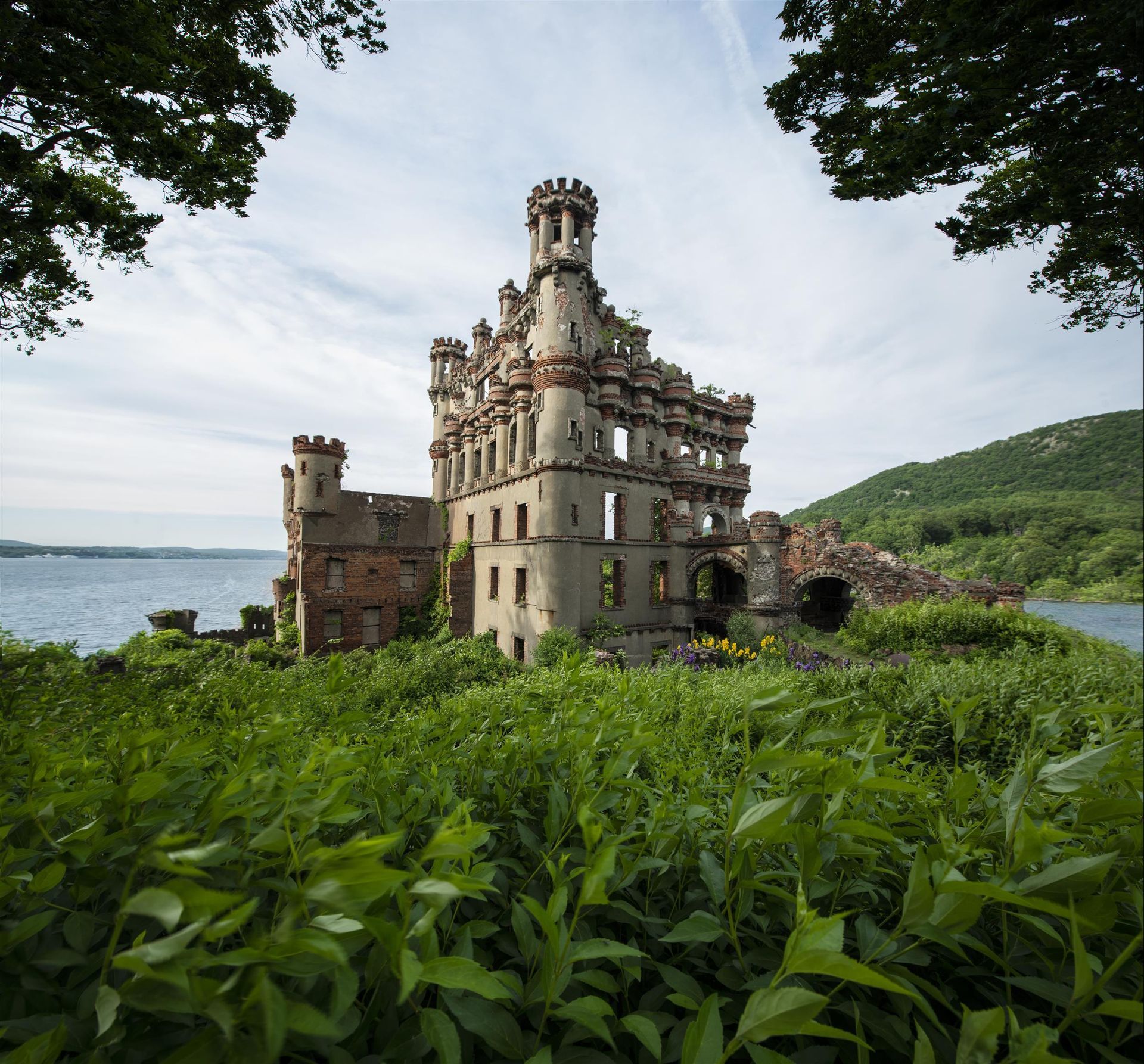 A large castle is sitting on top of a hill next to a body of water.