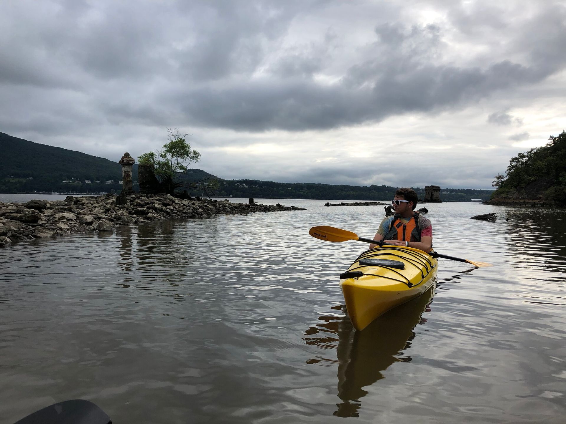A man is paddling a yellow kayak on a lake.