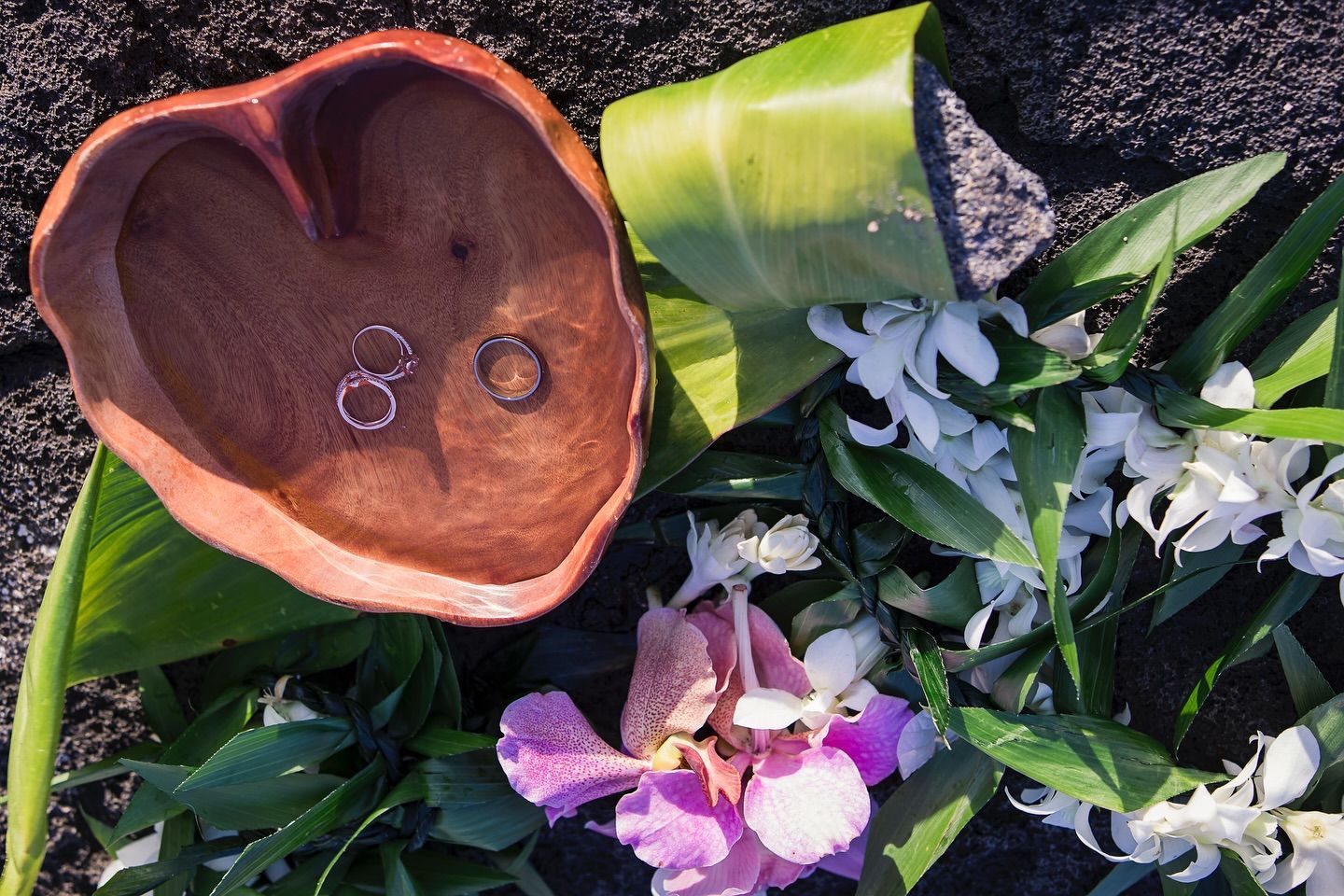 Fallen flower bouquet with purple orchids, white blooms, and a copper bowl on dark pavement