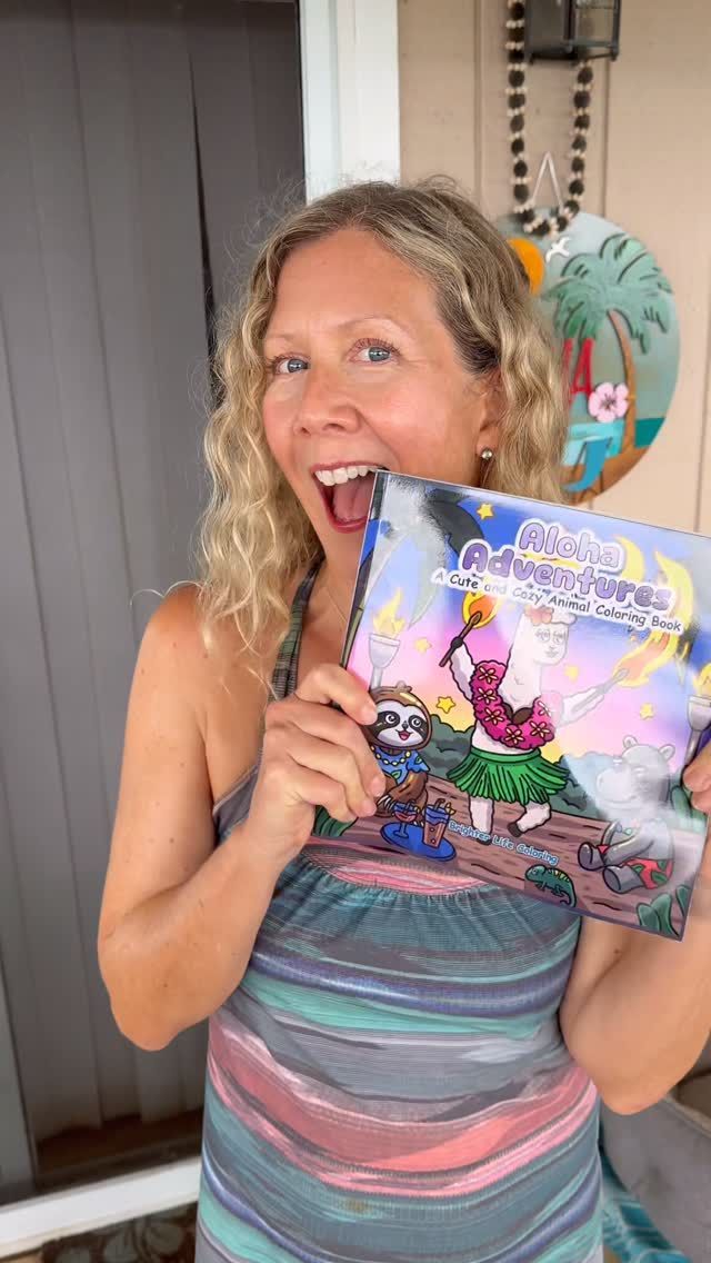 Woman smiling and holding a colorful illustrated book on a porch