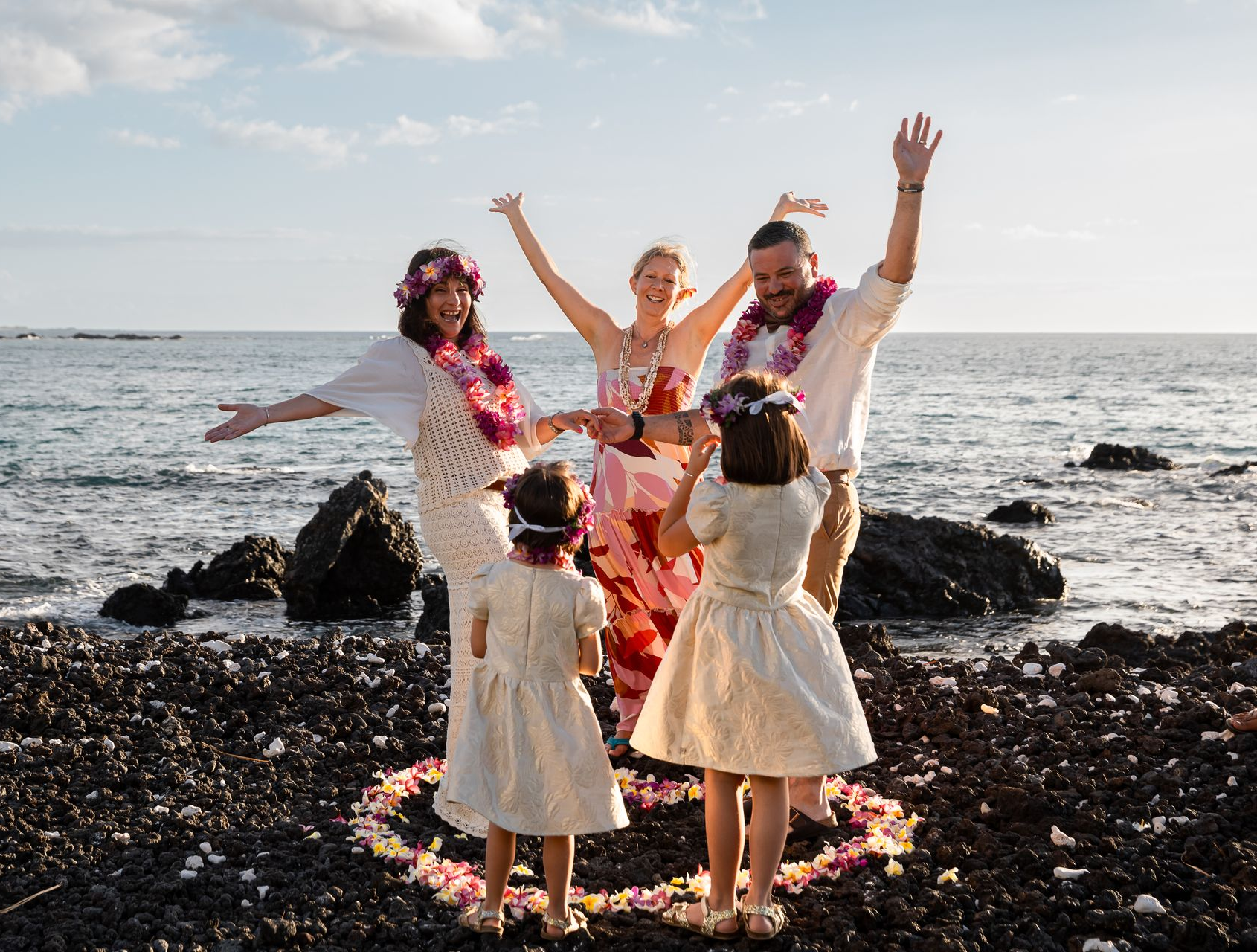 Couple holding hands at outdoor wedding ceremony by Simple Kona Beach Weddings on rocks near water.