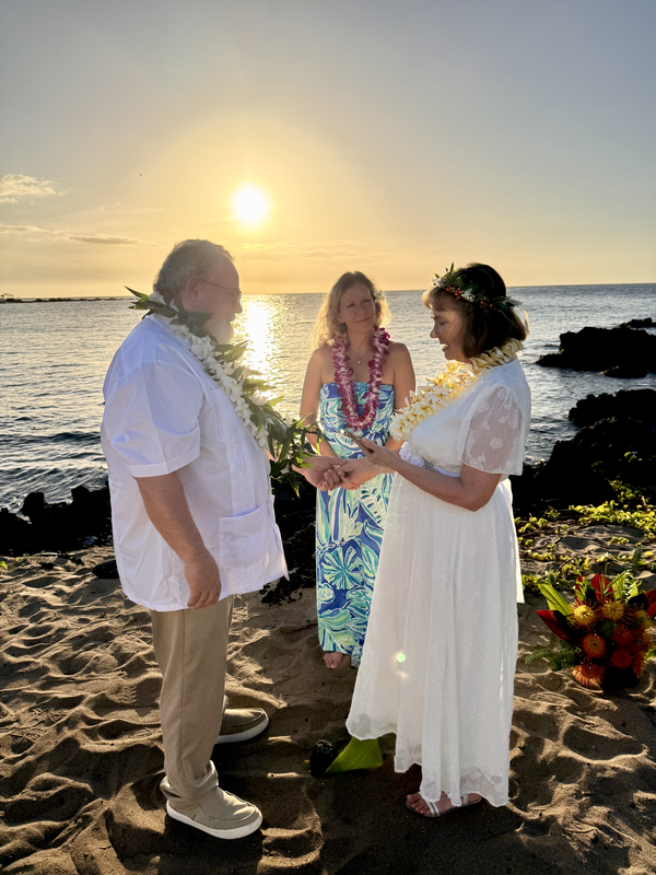 Couple exchanging rings at beach wedding ceremony at sunset.