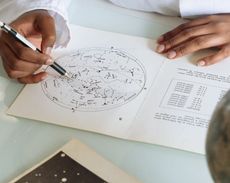 A person is writing on a piece of paper with a pen.