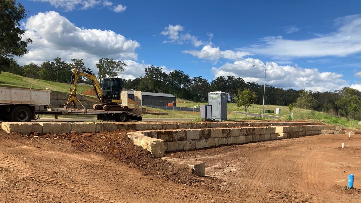 A construction site with a truck and an excavator in the background.