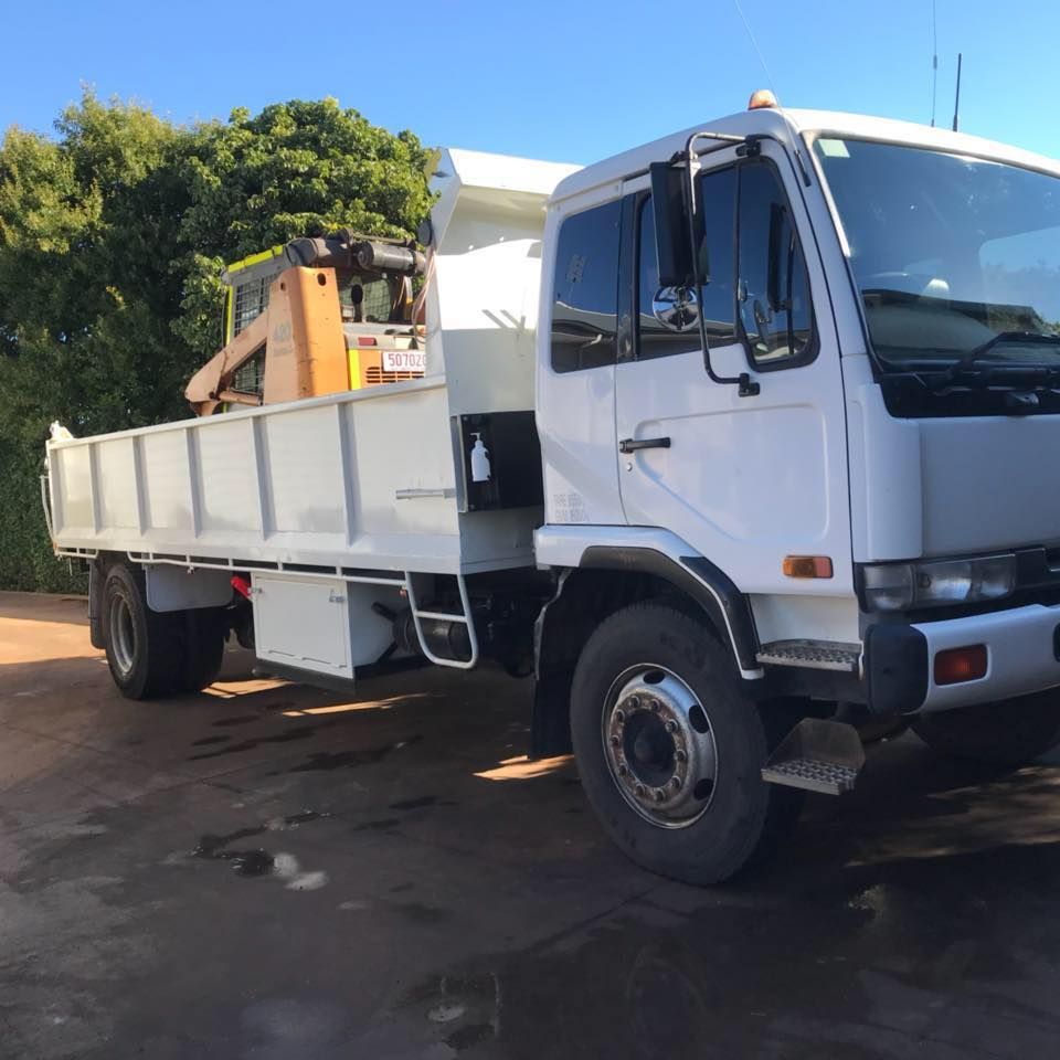 A white dump truck is parked on a dirt road